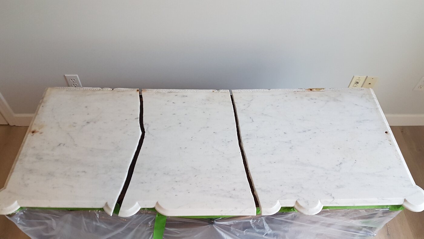 Antique marble table top broken into sections with open cracks before repair