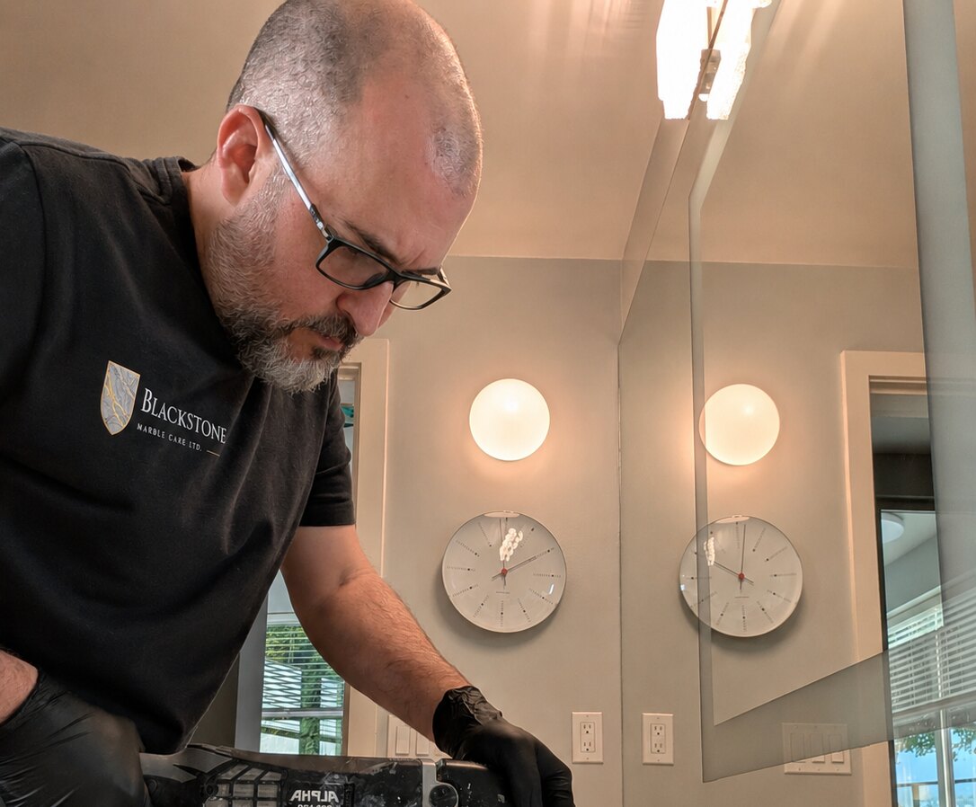 Rob Murray wet-polishing a marble bathroom vanity with a hand polisher