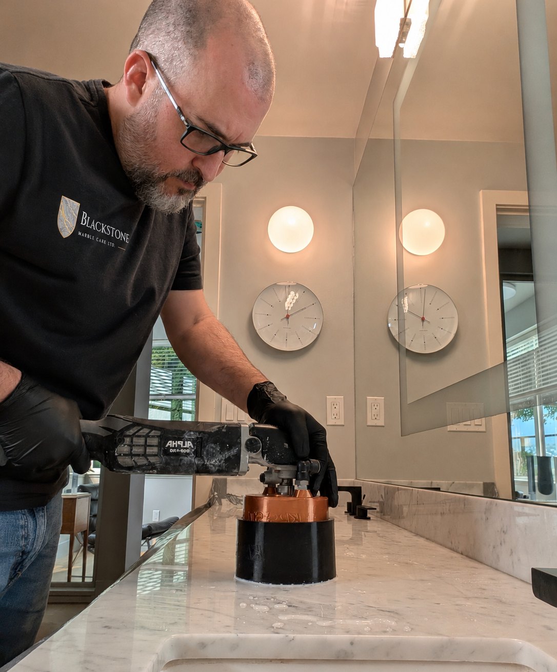 Rob Murray wet-polishing a marble bathroom vanity with a hand polisher
