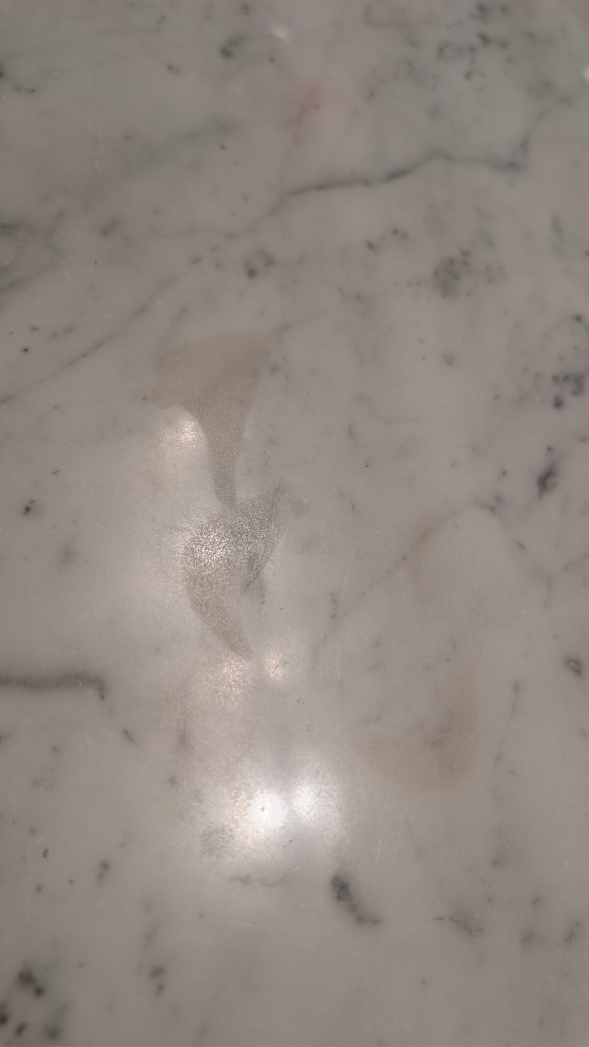 Close-up of acid etch marks dulling the surface of a polished marble countertop